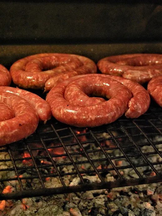 Boerewors coiled into a spiral on a grid over the coals