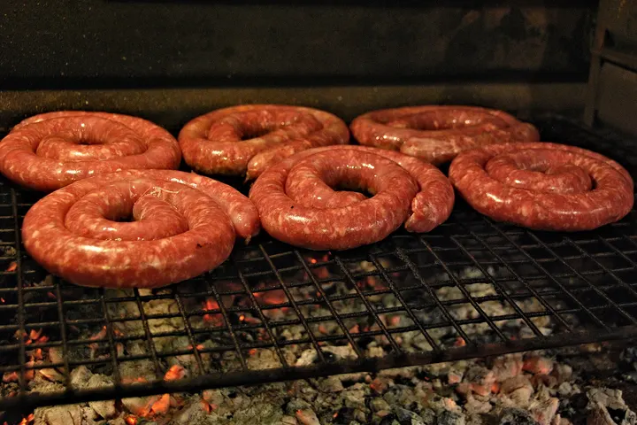 Zur Spirale aufgerollte Boerewors auf einem Rost über der Glut