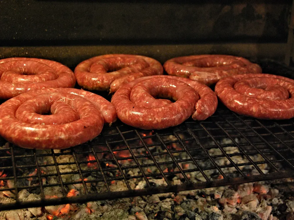 Zur Spirale aufgerollte Boerewors auf einem Rost über der Glut