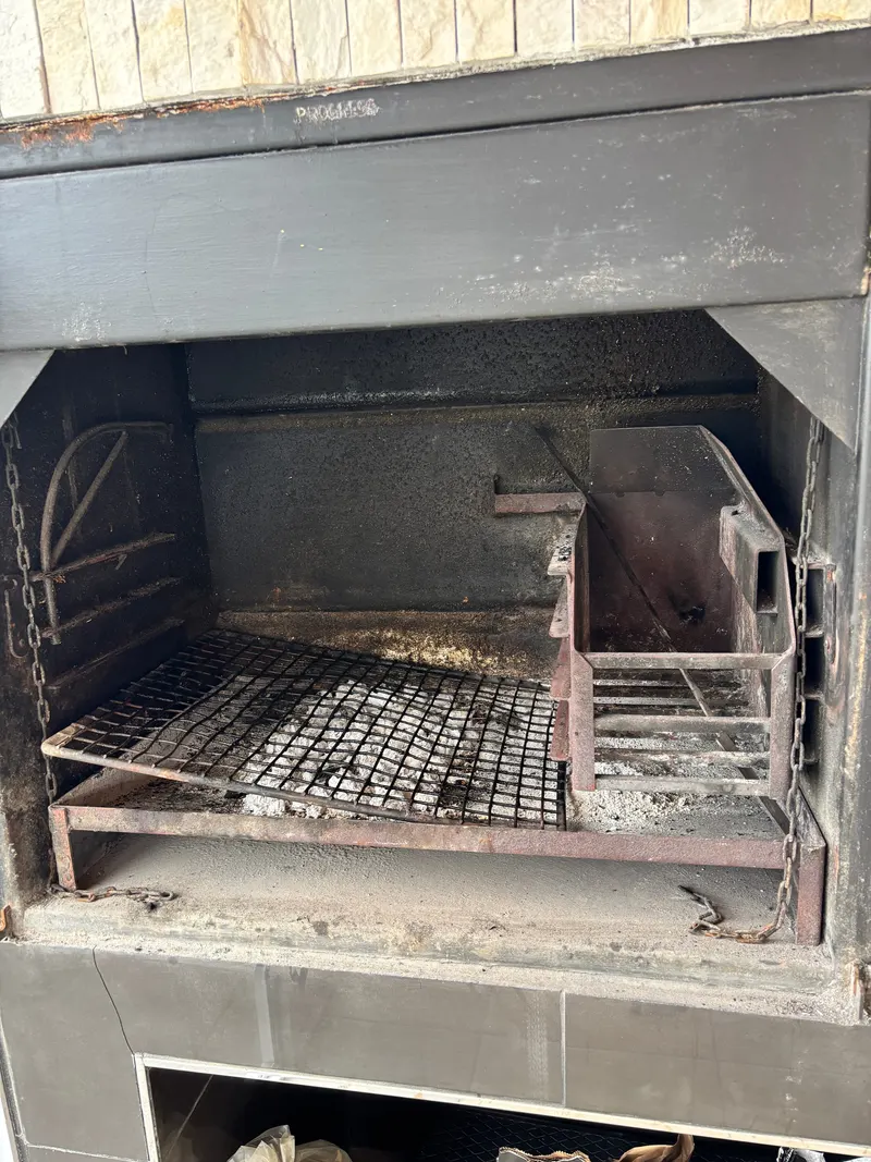 Leere gemauerte Braai von vorn: Rost, Aschefach und der höhenverstellbare Rostträger