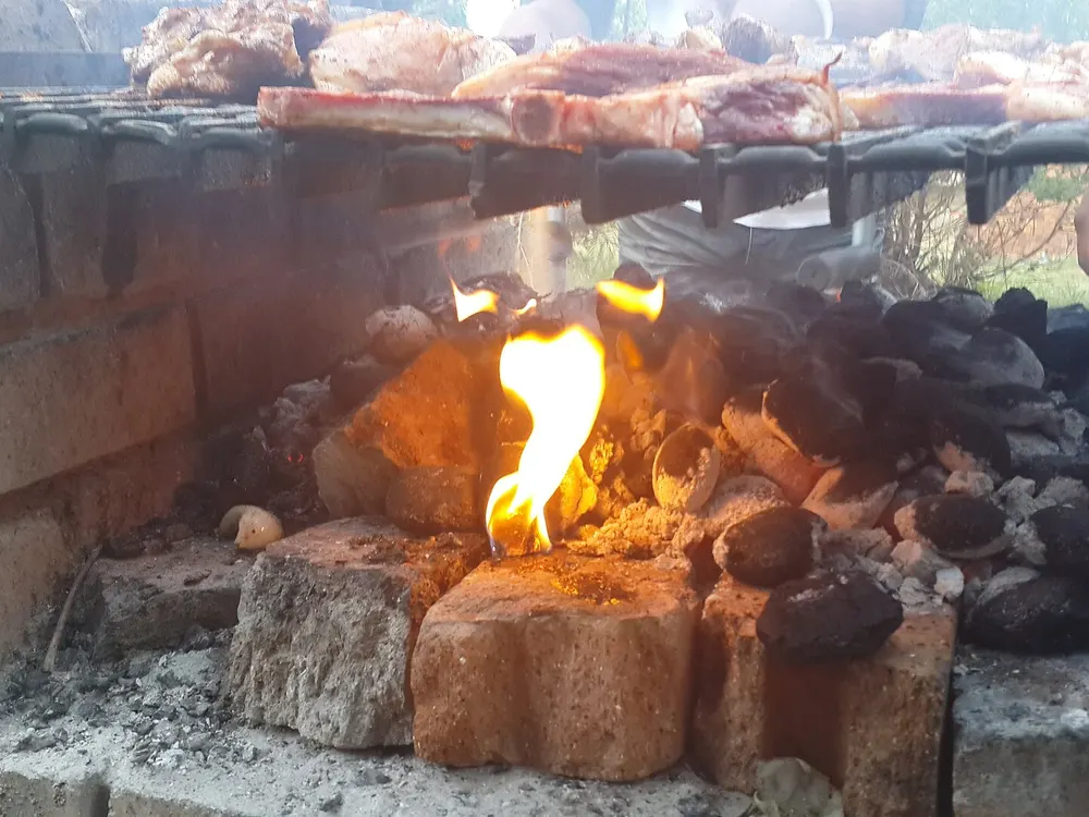 Burnt-down coals with a layer of grey ash beneath a braai grid