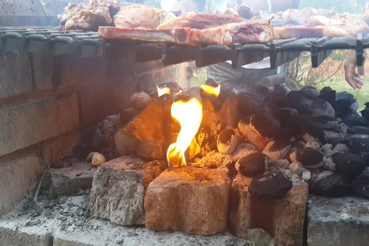 Burnt-down coals with a layer of grey ash beneath a braai grid