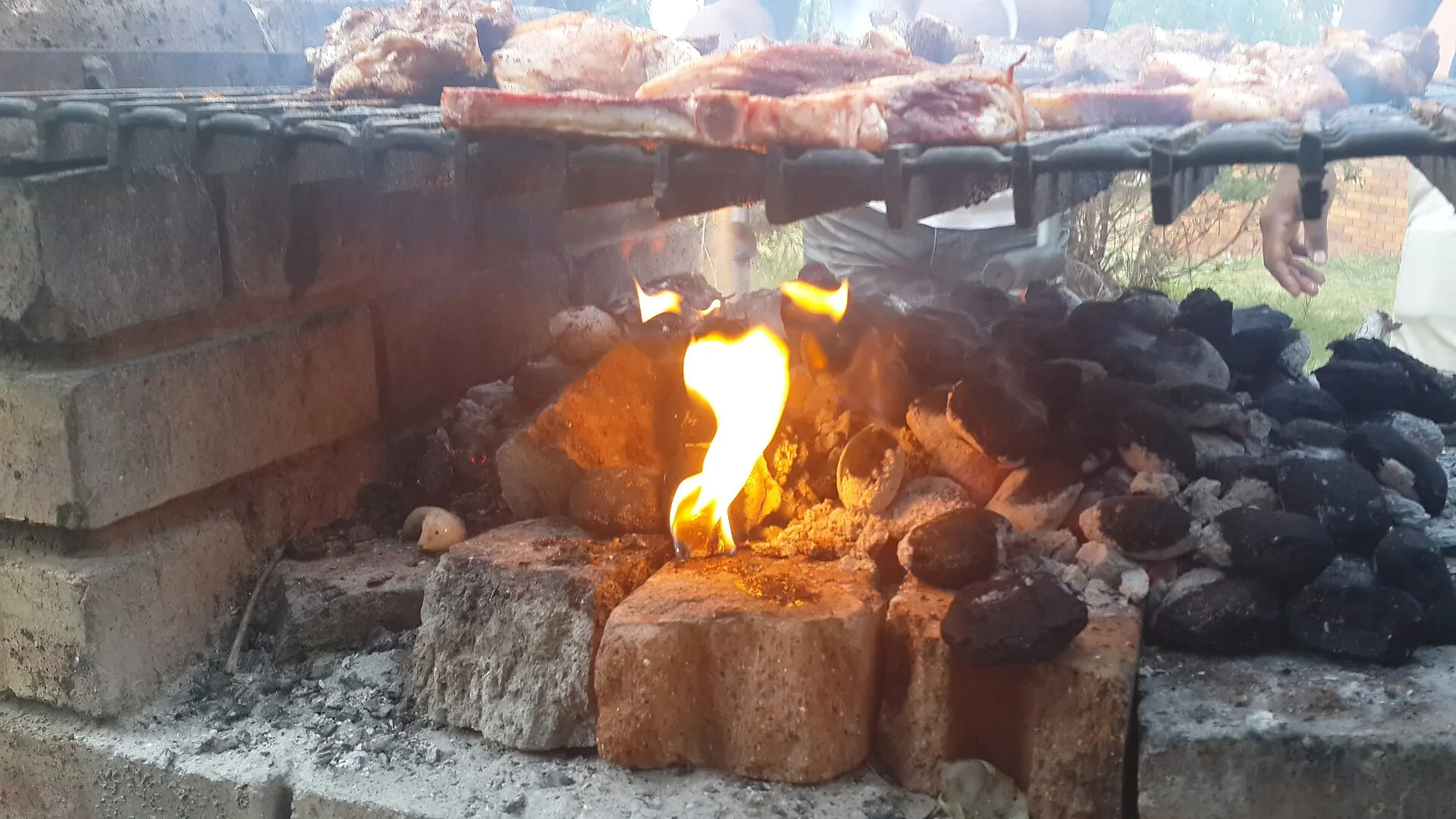 Heruntergebrannte Glut mit grauer Ascheschicht unter einem Grillrost