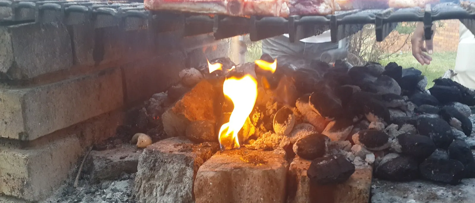 Heruntergebrannte Glut mit grauer Ascheschicht unter einem Grillrost