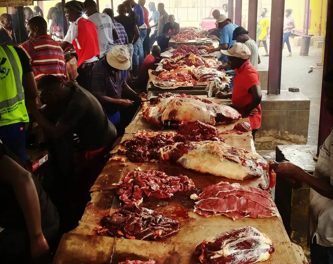 Lange Tische voller Fleisch an einem Braai-Stand, davor die Kundschaft