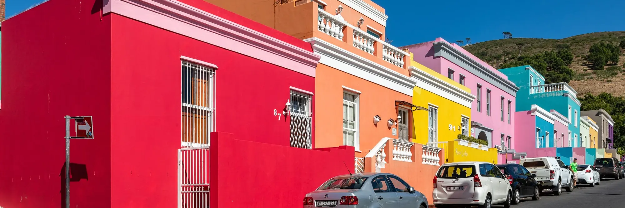 Bunt gestrichene Häuser an der Wale Street im Bo-Kaap, dahinter der grüne Hang des Signal Hill