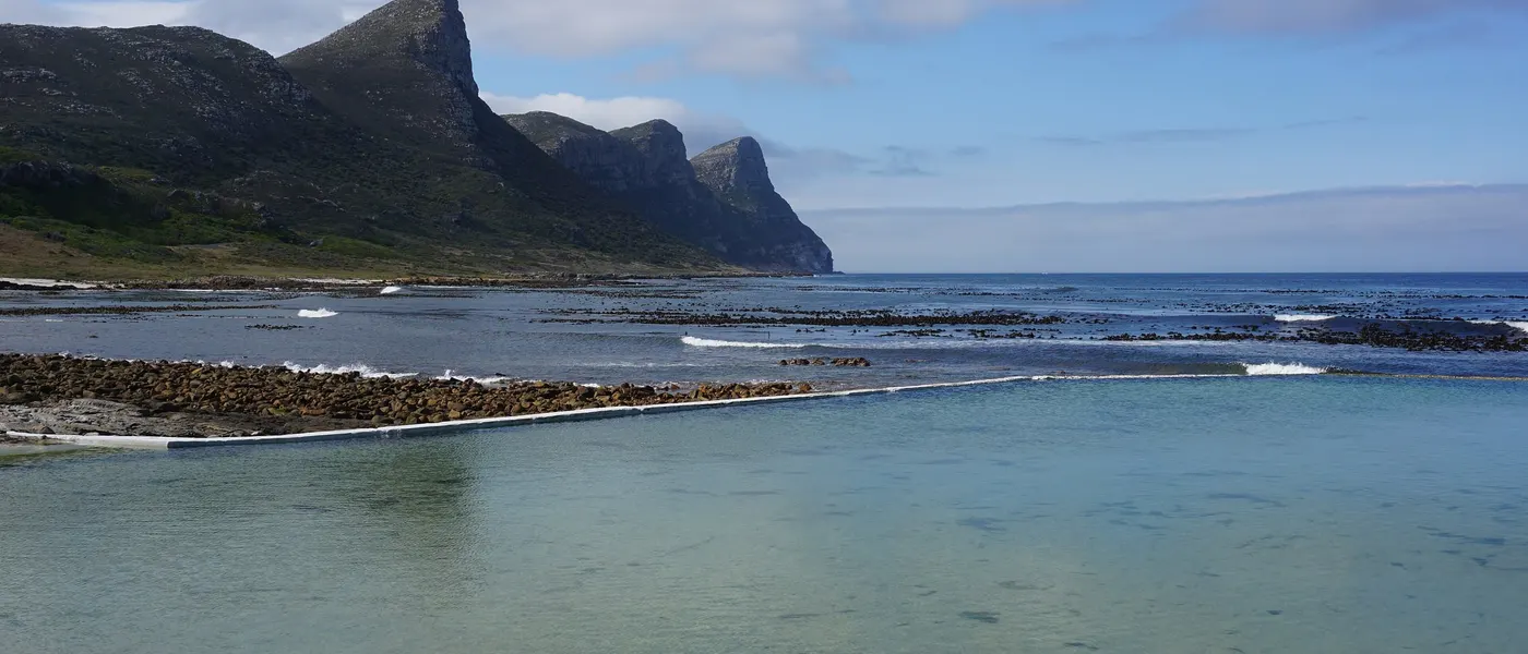 Gemauerter Gezeitenpool an der Felsküste von Bordjiesrif, dahinter die Berge des Kaps der Guten Hoffnung