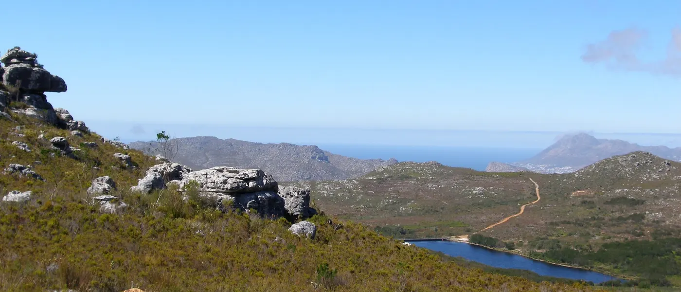 Blick über die Fynbos-Hänge des Silvermine Nature Reserve auf den Stausee und das Meer dahinter