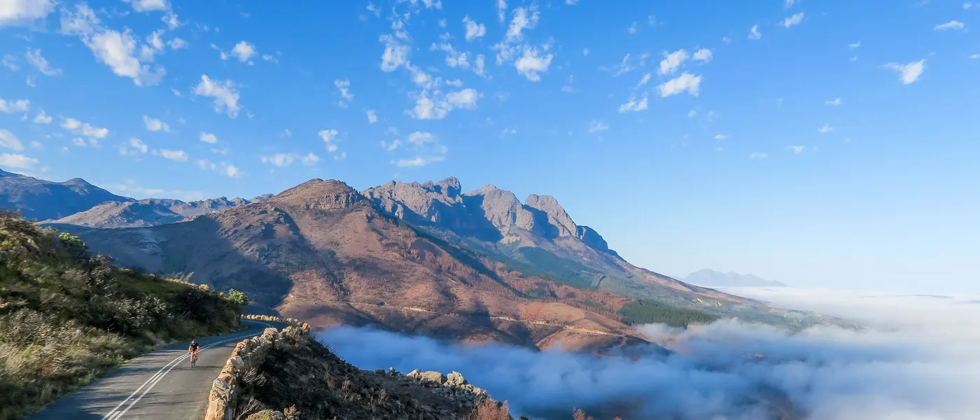 Die Passstraße des Bainskloof über einem Wolkenmeer, dahinter die Kämme des Limietberg