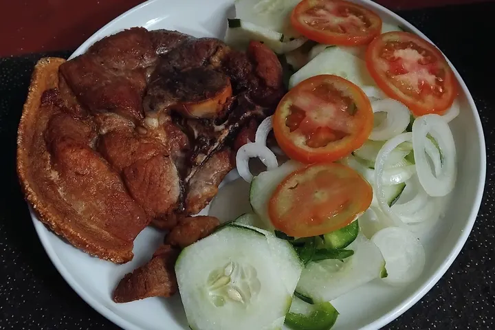 Gebratener Schweinebauch mit knuspriger Kante, dazu Tomaten- und Gurkenscheiben