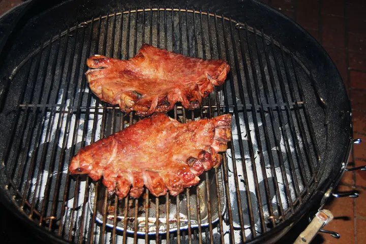 Zwei Leitern Schweinerippchen auf dem Rost über der Glut
