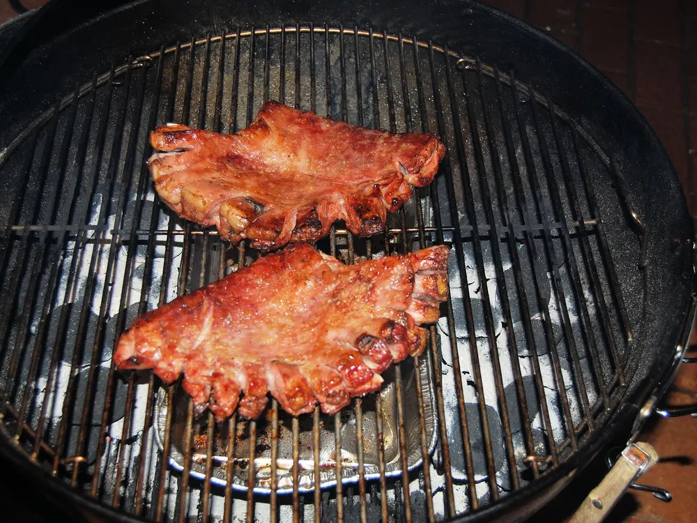 Zwei Leitern Schweinerippchen auf dem Rost über der Glut