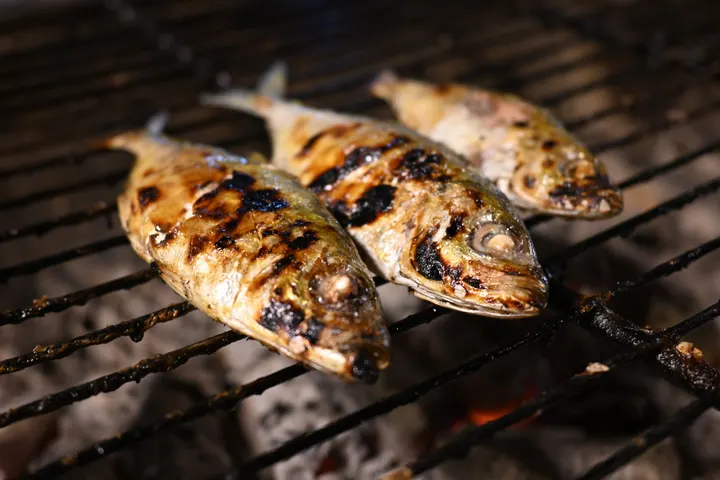 Ganze Fische über heißer Glut, die Haut vom Rost gestreift
