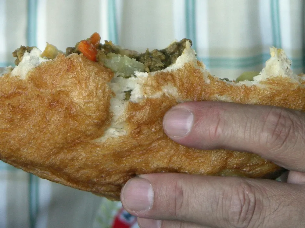 Aufgeschnittener Vetkoek, gefüllt mit Curry-Hack
